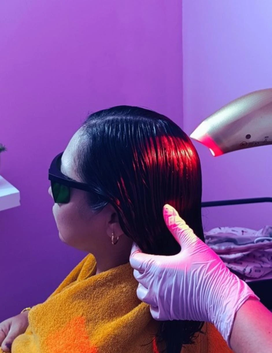 Clienta con lentes de protección recibiendo photon láser en el cabello en el salón Infinity Beauty